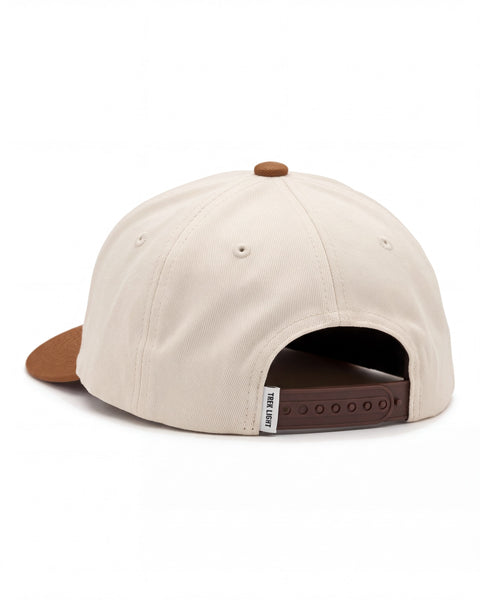 Back view of the Happy To Be Here Hat in cream twill with a brown brim, button and snap strap, on white.