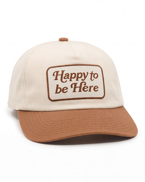 Happy To Be Here Hat in cream with a brown brim and a brown embroidered patch reading "Happy to be Here," on white.