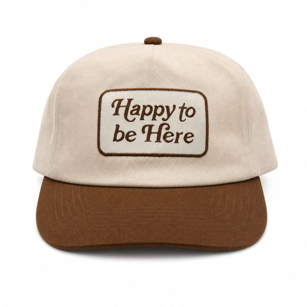 Happy To Be Here Hat featuring beige fabric with brown visor and embroidered lettering.