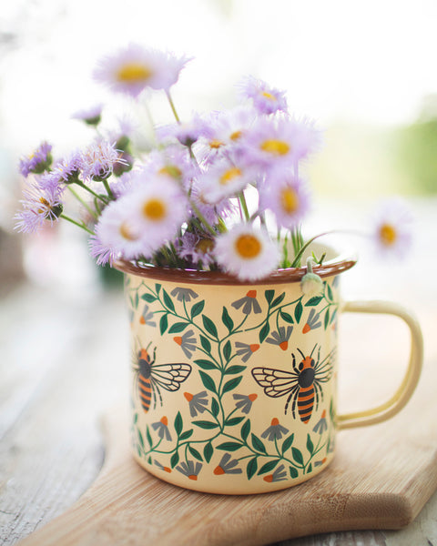 Honey Bee Enamel Mug 16oz filled with purple flowers, featuring a beautiful honey bee design.
