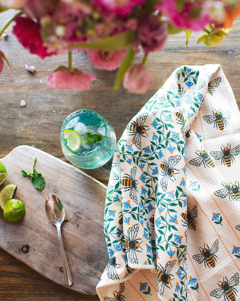 Honey Bee Kitchen & Tea Towel displayed with a drink and fresh ingredients, showcasing its vibrant, eco-friendly design.