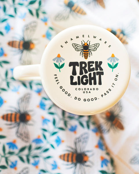 Honey Bee Kitchen & Tea Towel with an enamel mug and floral design background.