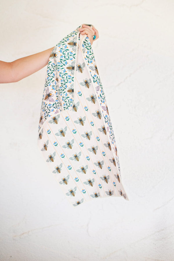 Honey Bee Kitchen & Tea Towel held up, showcasing vibrant bee patterns on eco-friendly fabric.