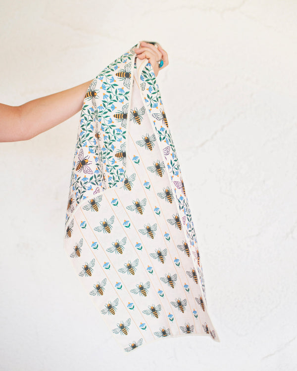Honey Bee Kitchen & Tea Towel held up, showcasing vibrant bee patterns on eco-friendly fabric.