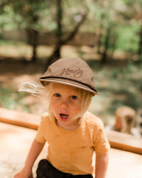 Toddler wearing Howdy Kids Hat in a playful outdoor setting, enjoying a sunny day.