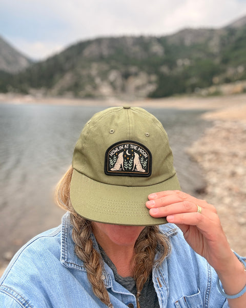 Woman wearing Howlin' At The Moon Hat by the lake, showcasing its design and style.