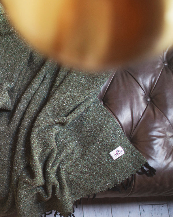 Humboldt Blanket draped on a leather couch, showcasing earthy tones and natural textures, perfect for cozy comfort.