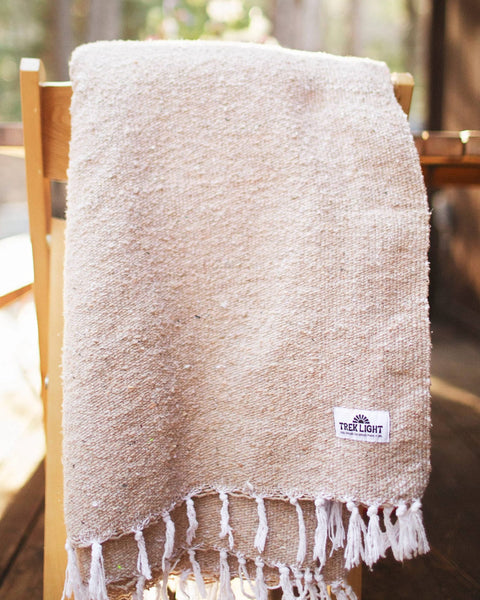 Huntington Blanket draped over a wooden chair, handcrafted, cozy and perfect for beach vibes or household use.