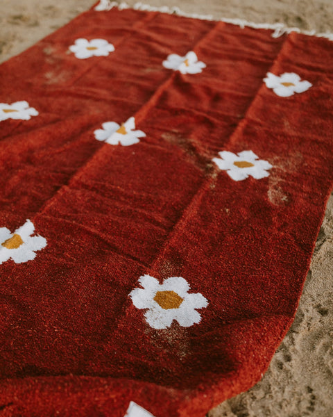 Lazy Daisy Blanket with charming daisy pattern on a red background, perfect for relaxing moments. Explore cozy with Trek Light.