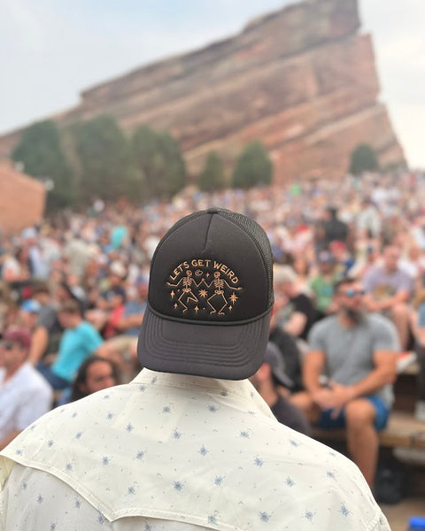 Back of a person wearing the black Let's Get Weird Hat in a crowd at Red Rocks Amphitheatre, Trek Light
