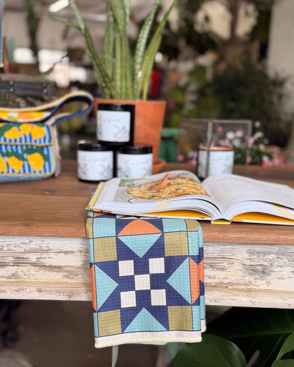 Lucky Stars Kitchen & Tea Towel hanging over a rustic table with plants and kitchen items.