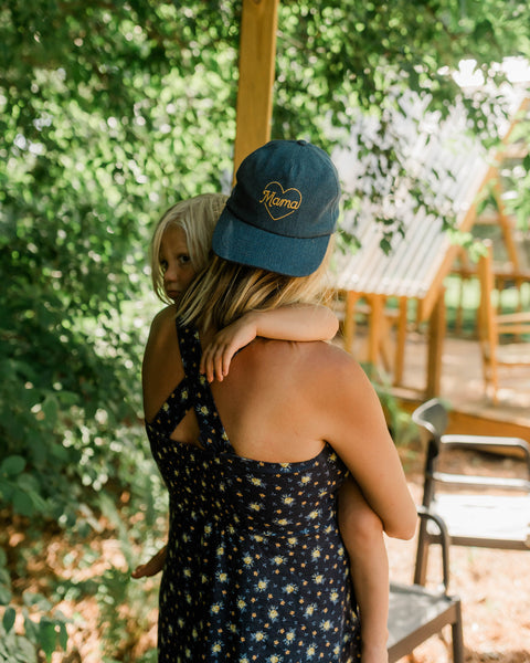 Mama Hat worn by a woman holding a child, showcasing its comfortable design and stylish look.