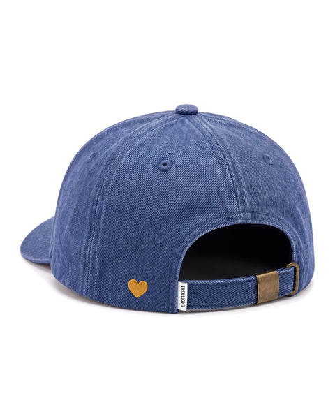 Mama Hat in blue denim, seen from the back, with a small gold embroidered heart and a brass strap buckle, on white.