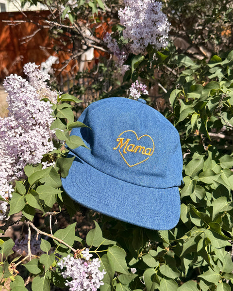 Mama Hat on a bed of lilac flowers, featuring a heart design and adjustable fit for comfort.