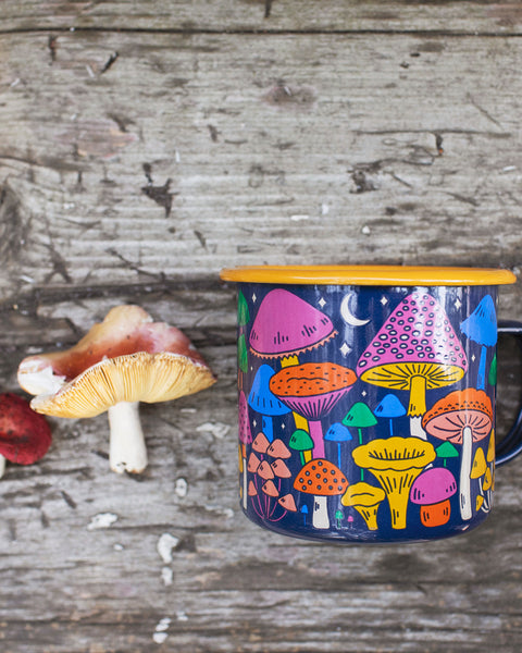 Midnight Mushroom Enamel Mug 16oz featuring vibrant mushroom design against rustic wood background