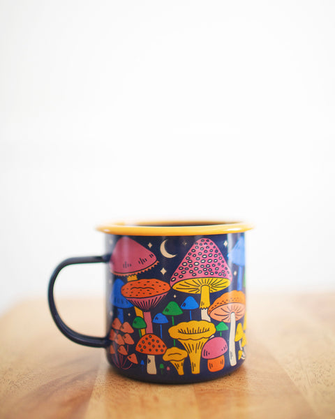 Midnight Mushroom Enamel Mug 16oz with colorful mushroom design by Trek Light on a wooden surface.
