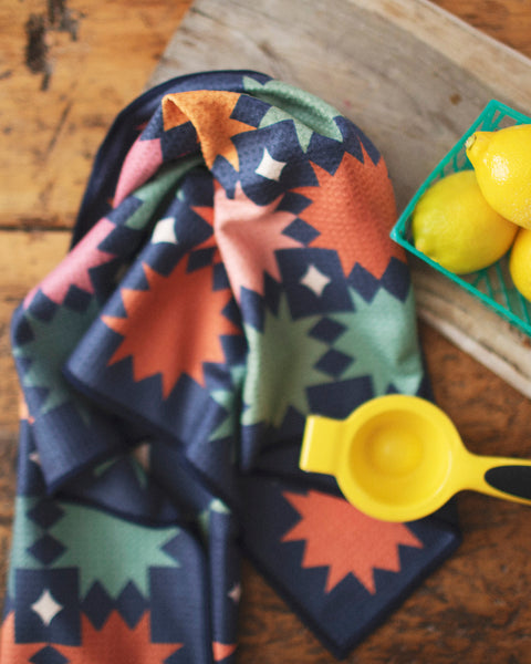 Colorful Moon Phase Kitchen & Tea Towel with lemons and a juicer on a wooden table.