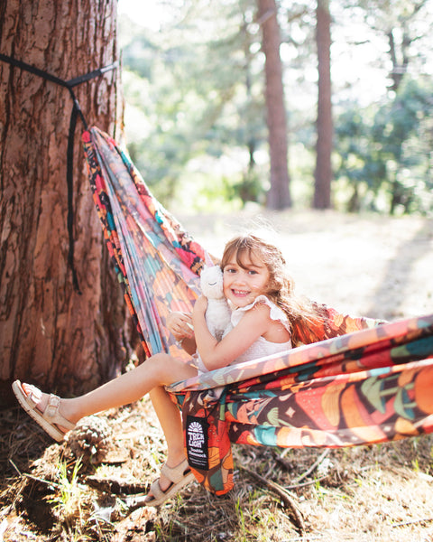 Girl enjoying in a Double Hammock & Pro Hanging Straps (Midnight Mushroom Print) in a sunny forest.