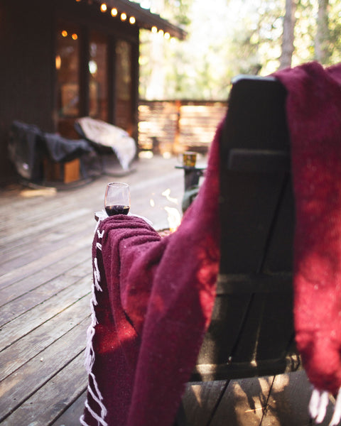 Napa Blanket draped over a chair with a glass of red wine, perfect for cozy evenings outdoors.
