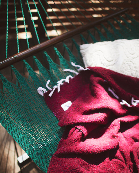 Cozy Napa Blanket draped over a green hammock, perfect for relaxation and outdoor enjoyment.