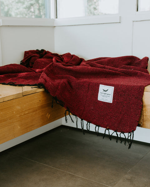 Cozy Napa Blanket in rich red, handwoven from recycled materials by Trek Light. Perfect for naps and eco-conscious relaxation.