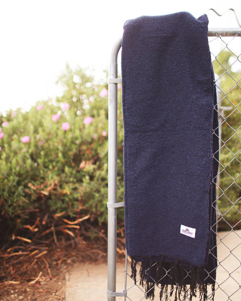 Newport Blanket hanging on a fence, showcasing its rich navy color and texture.