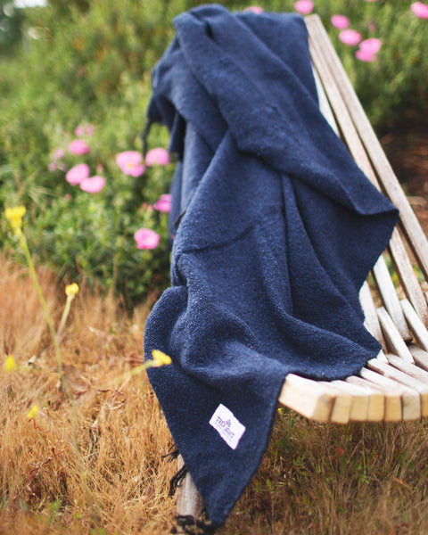 Newport Blanket draped over a bench in a garden, showcasing its coastal charm and handcrafted design.