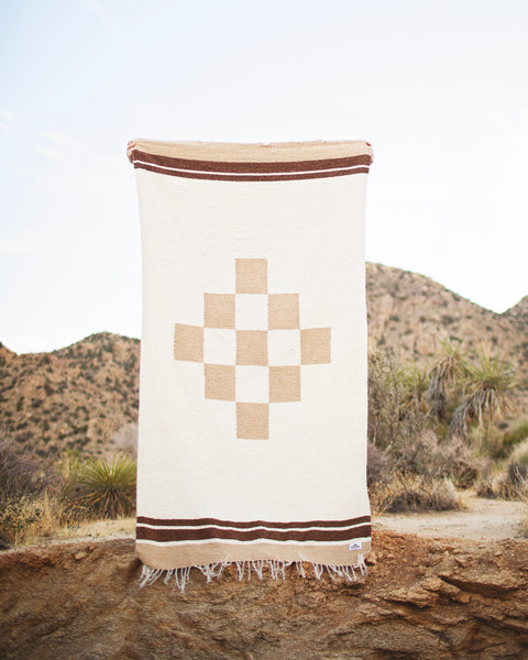 Beautiful handwoven North Star blanket, made from recycled clothing, displayed outdoors. Versatile, cozy, and sustainable. By Trek Light.