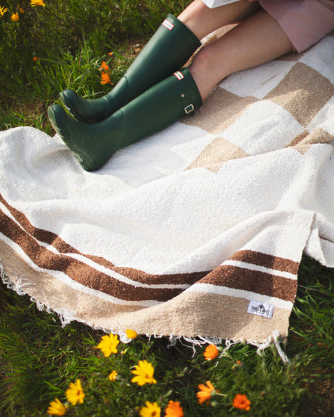 Cozy handwoven North Star blanket made from recycled clothing, showcasing beautiful natural tones. Perfect for outdoor relaxation. By Trek Light.