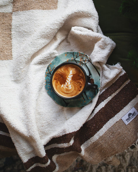 North Star Blanket draped on a couch with a coffee cup on a decorative plate.