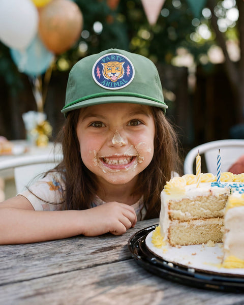 Child wearing a Party Animal Kids Hat, smiling with cake on face, celebrating a birthday party.