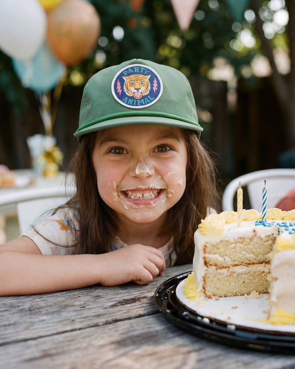 Child wearing a Party Animal Kids Hat, smiling with cake on face, celebrating a birthday party.