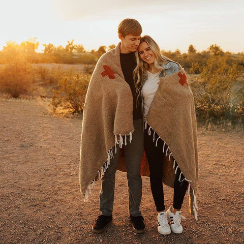 Couple embracing under the Positive Vibrations Blanket during sunset in a natural setting.