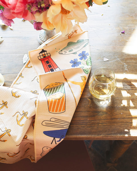 Rhode Island Kitchen & Tea Towel featuring vibrant designs of lighthouses, fish, and drink illustrations.