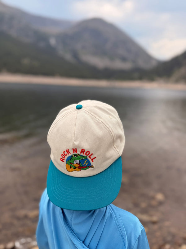 Child wearing a Rock N Roll Kids Hat while enjoying outdoor adventures near a lake.