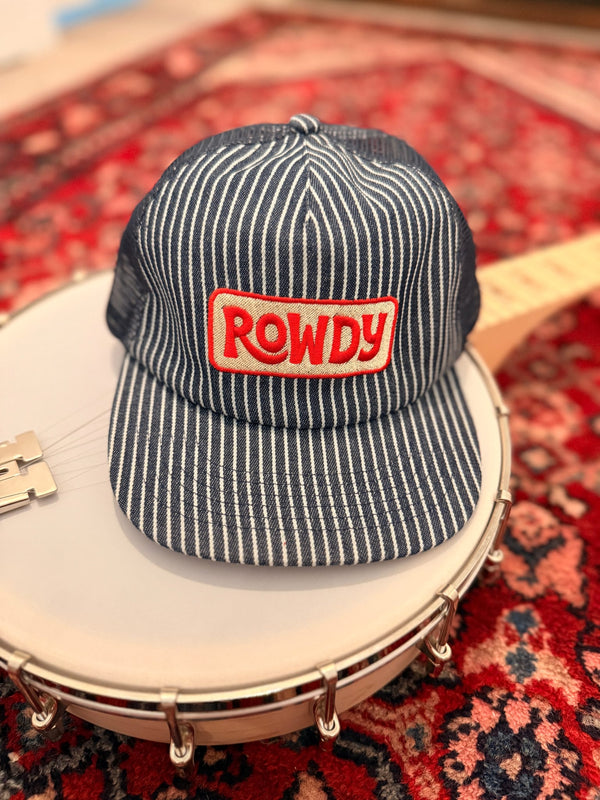 Rowdy Hat resting on a banjo, showcasing its striped design and vibrant logo, perfect for all-day wear.