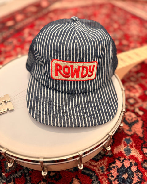 Rowdy Hat resting on a banjo, showcasing its striped design and vibrant logo, perfect for all-day wear.