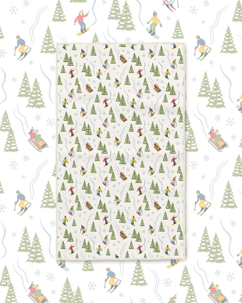 Snow Day Kitchen & Tea Towel with skiers, sledders and green pine trees on a white background