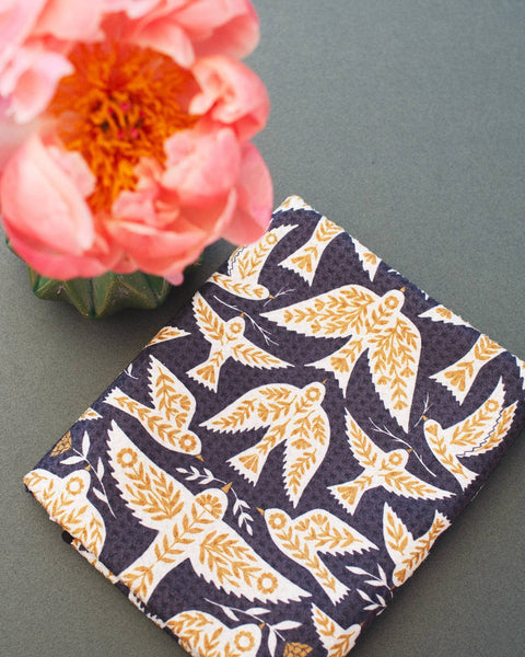 Songbird Kitchen & Tea Towel featuring a vibrant bird design with a pink flower in the background.