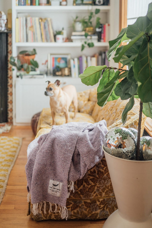 Cozy lavender Sonoma Blanket on a sofa, handwoven from recycled clothing materials, perfect for creating a beautiful, serene space. By Trek Light.