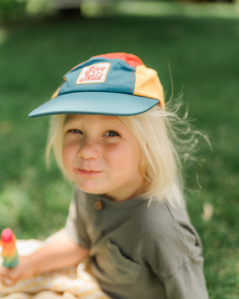 Child wearing a colorful Stay Wild Kids Hat while enjoying a day outdoors.