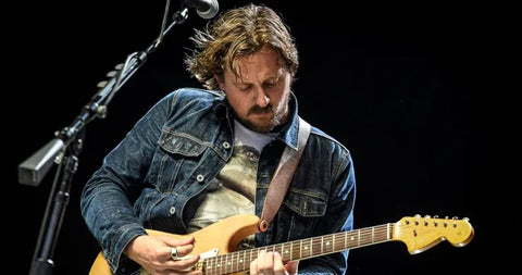 Johnny Blueskies playing electric guitar on stage with microphone in background