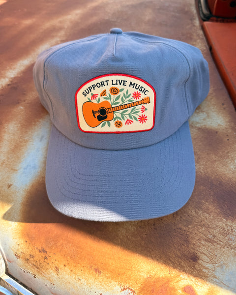 Support Live Music Hat displayed on a rustic surface, featuring a guitar and floral design.