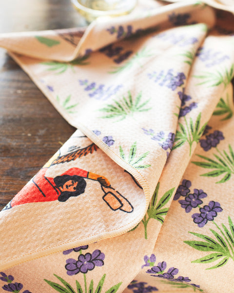 Texas Kitchen & Tea Towel featuring vibrant designs with flowers and a woman cooking, ideal for kitchen use.