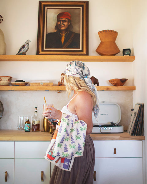 Woman in kitchen with Texas Kitchen & Tea Towel, showcasing vibrant design and eco-friendly features.