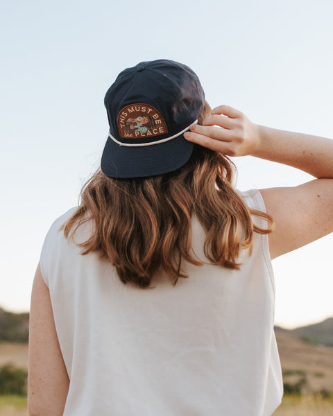 This Must Be The Place Hat (Mountains) worn outdoors with a scenic backdrop.