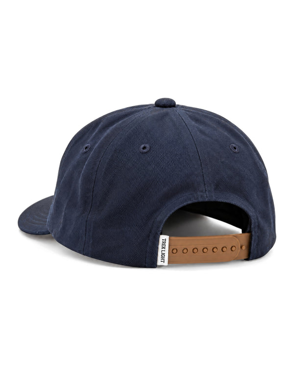This Must Be The Place Hat in Mountains, a navy cap seen from the back with a tan snap strap, on white.