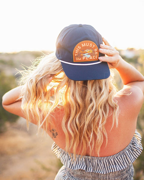 Woman wearing This Must Be The Place Hat (Mountains) outdoors during sunset.