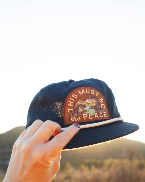 This Must Be The Place Hat (Mountains) held up against a beautiful outdoor setting.