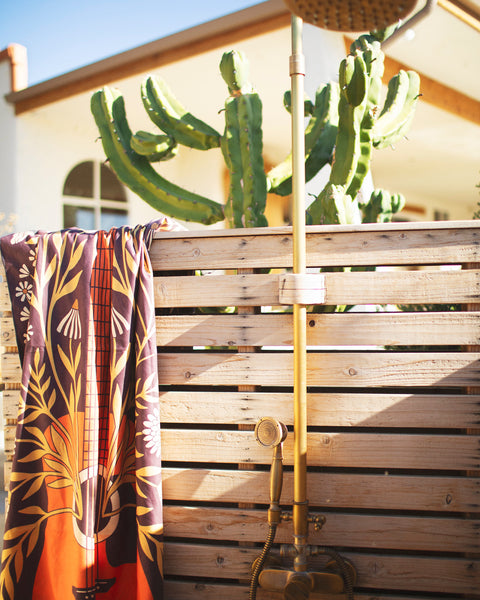Travelin' Light Wander & Travel Towel hanging near a cactus with a shower in a sunny outdoor setting.